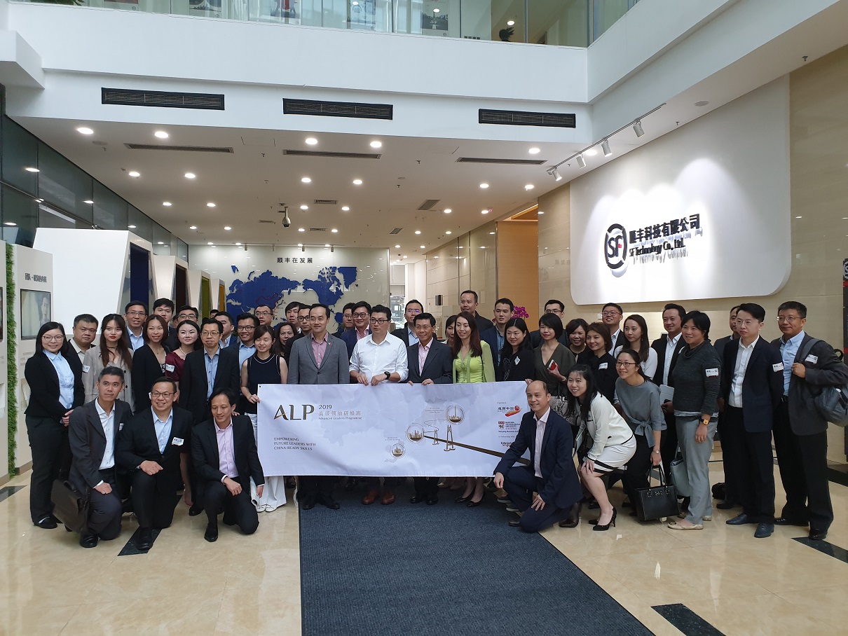 Group poses indoors holding an "ALP 2019" banner, with SF Technology Co., Ltd logo in background.